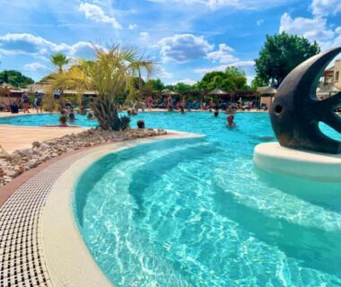 Piscine extérieure avec sculpture et palmiers au Mobil Home 2CH Bien Equipé Valras-Plage