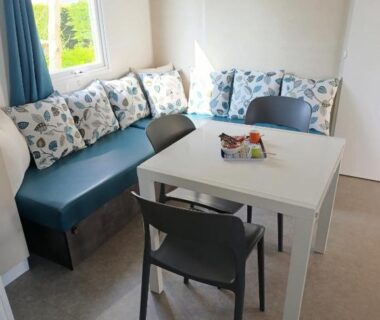 Coin repas avec banquette et coussins près de la fenêtre dans le Mobil Home 3 chambres