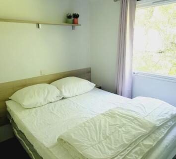 Chambre avec lit double et rideau dans le Mobil Home 4 6 pers climatisé Camping Eurolac