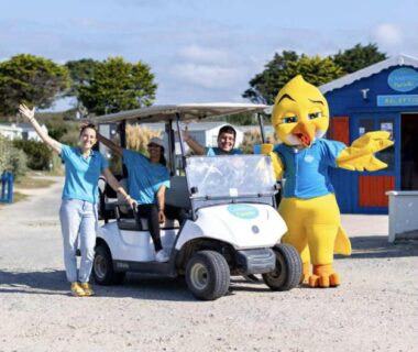 Accueil du camping avec voiturette, deux membres du personnel et mascotte au Mobil Home 4 places 2 chambres