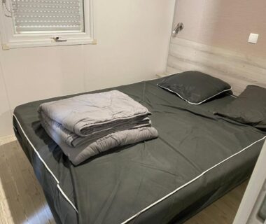 Chambre avec lit double et couvertures pliées dans le Mobil-Home 40 M2 Camping SIBLU La Carabasse
