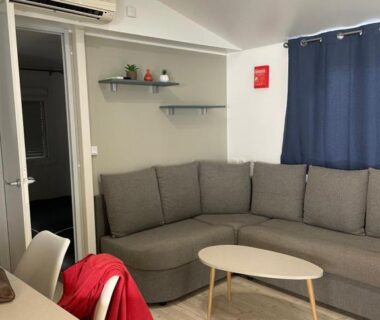 Salon avec canapé d'angle table basse et climatisation dans le Mobil-Home 40 M2 Camping SIBLU La Carabasse