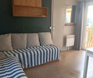 Séjour avec banquette rayée et climatisation dans le Mobil-Home 45 m2 du camping le Mar Estang 4 étoiles