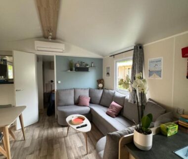Séjour avec canapé d'angle table basse et orchidée dans le Mobil-Home