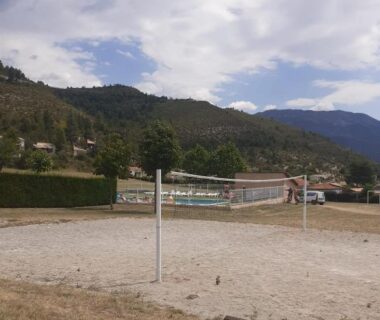 Terrain de volley sablonneux et piscine en arrière plan au Mobil-Home