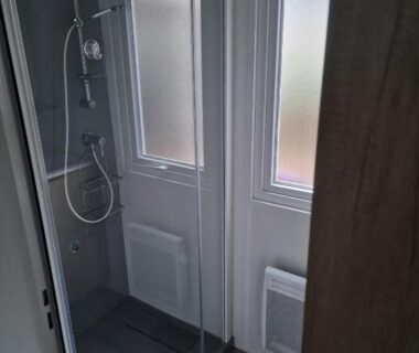 Salle d'eau avec douche vitrée et fenêtres dans le Mobil Home