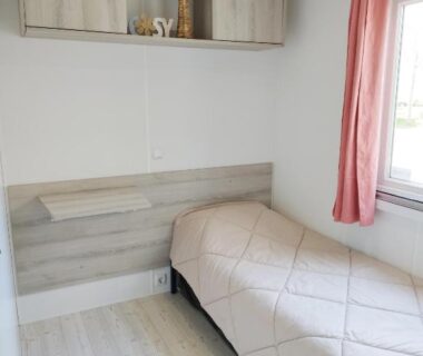 Chambre avec lit simple et fenêtre dans le Mobil Home 6-8p 3ch 2sb Clim