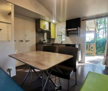 Intérieur salon avec kitchenette table et TV du Mobil Home 6 personnes 3 chambres à 25 MIN Puy duFou