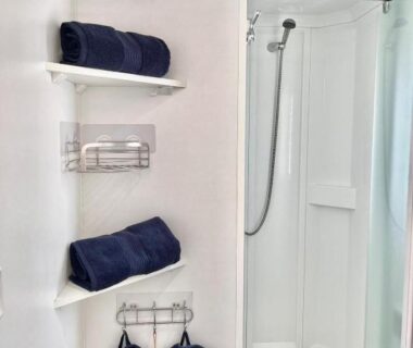 Salle de bain avec cabine de douche et serviettes bleu marine du Mobil Home Abricotiers 1