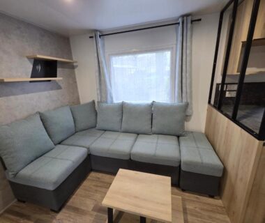Salon avec canapé d'angle dans le Mobil-Home BORA BORA 2022 au Domaine de Kerlann