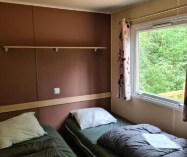 Chambre avec deux lits simples et fenêtre sur la verdure dans le Mobil Home Camiers
