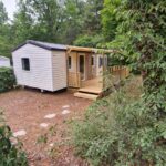 Mobil home entouré d'arbres avec terrasse en bois au Mobil Home Camiers