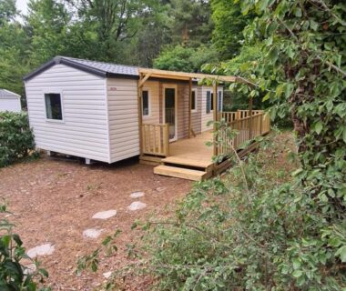 Mobil home entouré d'arbres avec terrasse en bois au Mobil Home Camiers