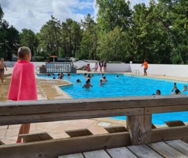 Piscine extérieure avec baigneurs et terrasse en bois au Mobil Home Camiers