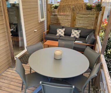 Terrasse couverte avec table ronde et salon extérieur du Mobil-Home Camping Club 5* Montalivet