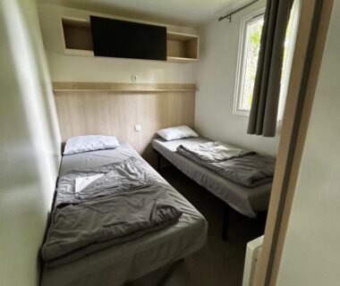 Chambre avec deux lits et télévision dans le Mobil Home Camping Marvilla Parks 5 lac Biscarosse