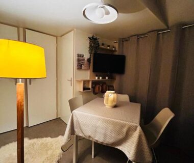 Intérieur coin repas avec table et télévision dans le mobil home Camping Marvilla Parks 5 lac Biscarosse