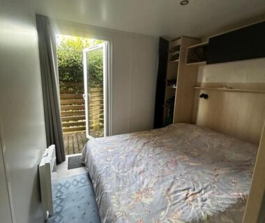 Chambre avec lit et porte-fenêtre dans le Mobil Home Camping Marvilla Parks 5 lac Biscarosse