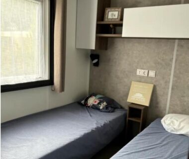 Chambre avec deux lits et fenêtre dans le Mobil Home Cap Ferret