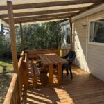 Terrasse en bois ombragée avec table et bancs du Mobil Home Confort TV CLIM 3Ch Narbonne Plage