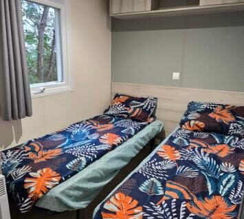 Chambre avec deux lits simples dans le mobil-home Le Bois Dormant 87