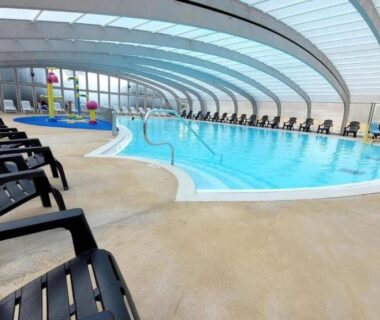 Piscine couverte avec chaises longues au Mobil-Home Le Bois Dormant 87