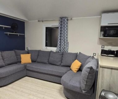 Séjour avec canapé d'angle et kitchenette du Mobil-Home Le Bois Dormant 87