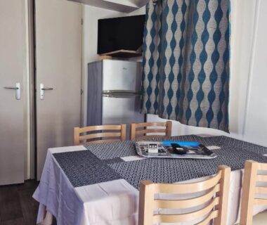 Coin repas avec table chaises télévision et frigo dans le mobil-home Le Dahlia-MH34