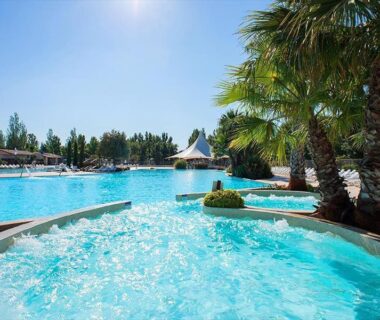 Piscine extérieure bordée de palmiers au Mobil-Home Les Terrasses Vias Plage