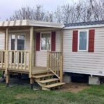 Sur la pelouse mobil home beige avec terrasse en bois au Mobil Home Litteau Calvados