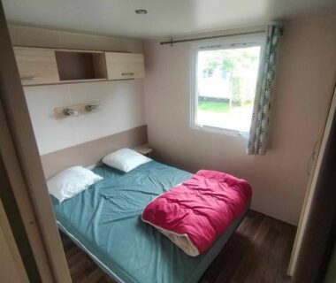 Chambre avec lit double et fenêtre dans le Mobil-Home Location de Vacances