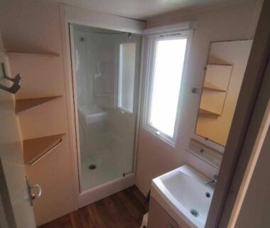 Salle de bain avec douche lavabo et fenêtre dans le Mobil-Home Location de Vacances