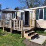 Terrasse en bois avec parasol et marches au Mobil Home Ohana Camping du Ried