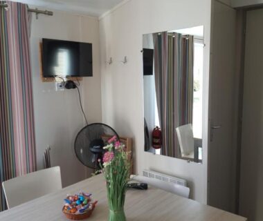 Coin repas intérieur avec vase de fleurs dans le mobil home Ohana Camping du Ried