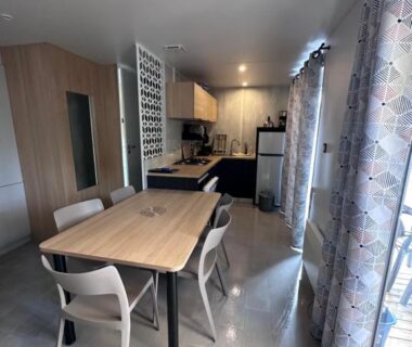Intérieur séjour avec table chaises et cuisine du Mobil Home Premium Camping Mayotte 5 CLIM TV LV R096