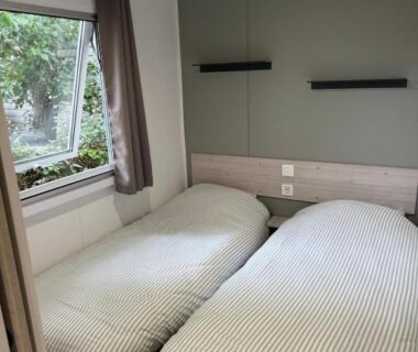 Chambre avec deux lits et fenêtre donnant sur jardin du Mobil Home SIBLU VALRAS PLAGE