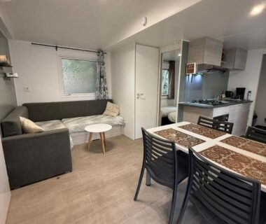 Salon avec canapé, table à manger et kitchenette dans le mobil home SIBLU VALRAS PLAGE