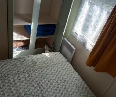 Chambre intérieure avec lit double lits superposés et fenêtre à rideau dans le mobil-home The Duck