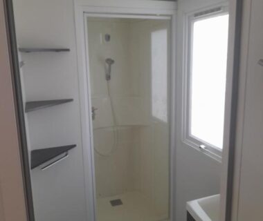 Salle d'eau avec cabine de douche et étagères dans le Mobil-Home VI07 Camping La Carabasse VIAS-PLAGE
