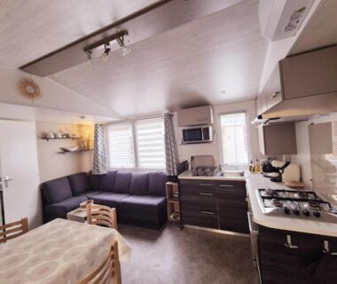 Intérieur séjour avec coin cuisine et canapé dans le Mobil Home Vias plage La Carabasse terrasse fermée hors saison