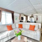 Salon lumineux avec canapé et cuisine ouverte dans le Mobil-Home Victory Camping Siblu 4****