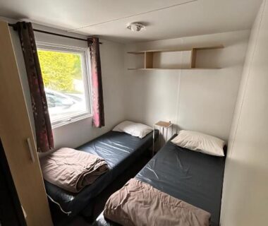 Chambre avec deux lits simples et fenêtre dans le Mobil-Home à Camiers Sainte Cécile