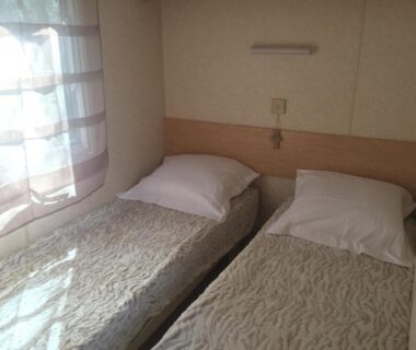 Chambre avec deux lits simples et fenêtre dans le Mobil Home à la ferme