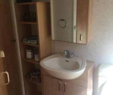 Salle de bains avec lavabo et miroir dans le Mobil Home à la ferme
