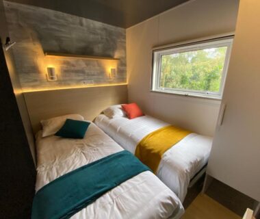 Chambre avec deux lits simples et fenêtre dans le Mobil Home camping La Civelle