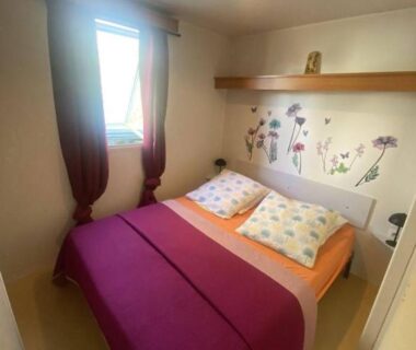 Chambre du mobil home avec lit double et décoration florale dans le Mobil Home camping l'escale