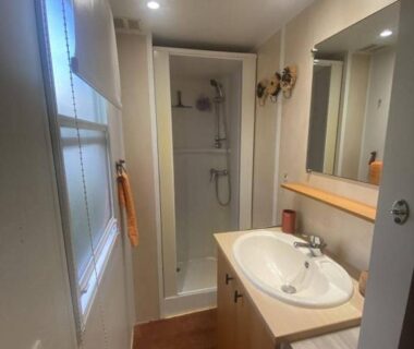 Salle de bains avec douche lavabo miroir et fenêtre dans le Mobil Home camping l'escale
