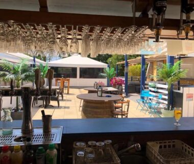 Terrasse du bar avec parasols tables et chaises au Mobil Home camping l'escale