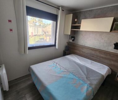Chambre avec lit et fenêtre dans le Mobil-Home climatisé de 40m2 à 800m de la plage