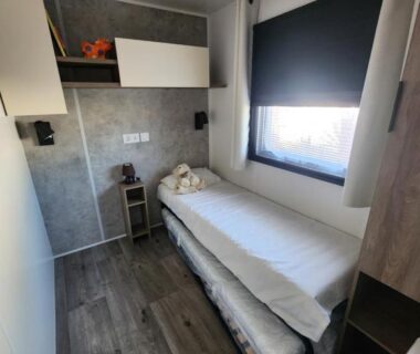 Chambre avec lit gigogne et store à la fenêtre dans le Mobil-Home climatisé de 40m2 à 800m de la plage